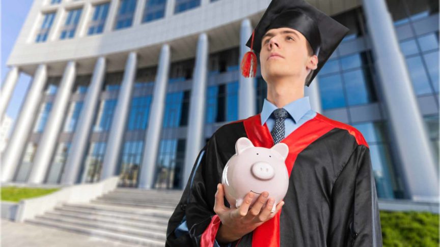 College graduate holding piggy bank