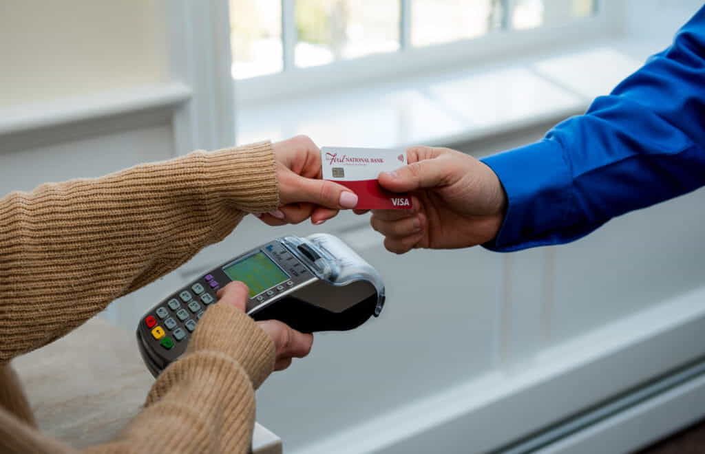Person swiping a credit card from The First.